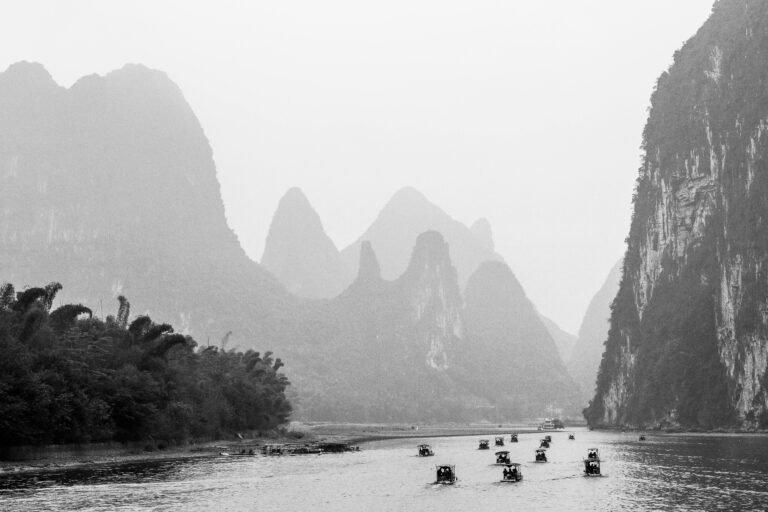 Black and white view of the Li River with boats and karst mountains in Guilin, China.